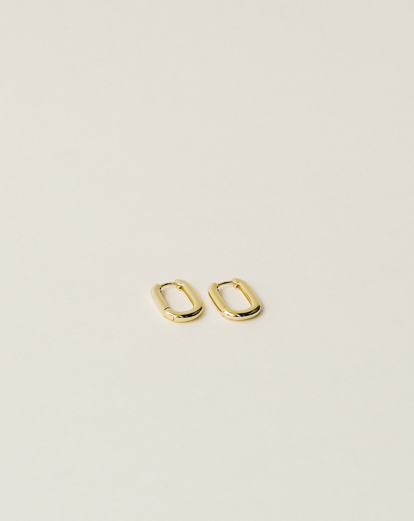 timeless and versatile oval shape huggie earrings handcrafted from 925 sterling silver plated in 18k gold. slow fashion trend 2020.