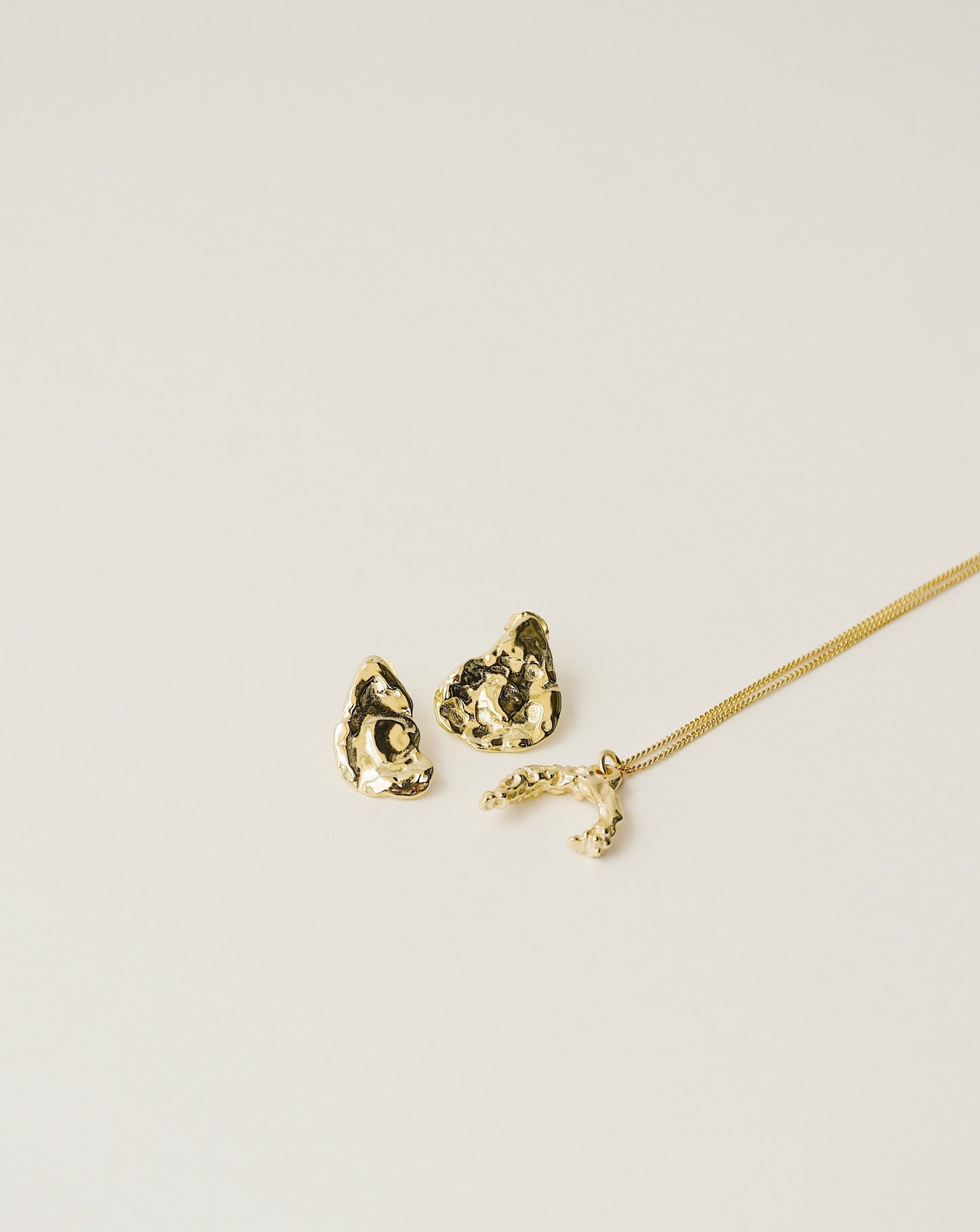 irregularly shaped stud earrings and necklace handcrafted from 925 sterling silver plated in 18k gold. 2020 slow fashion trend.