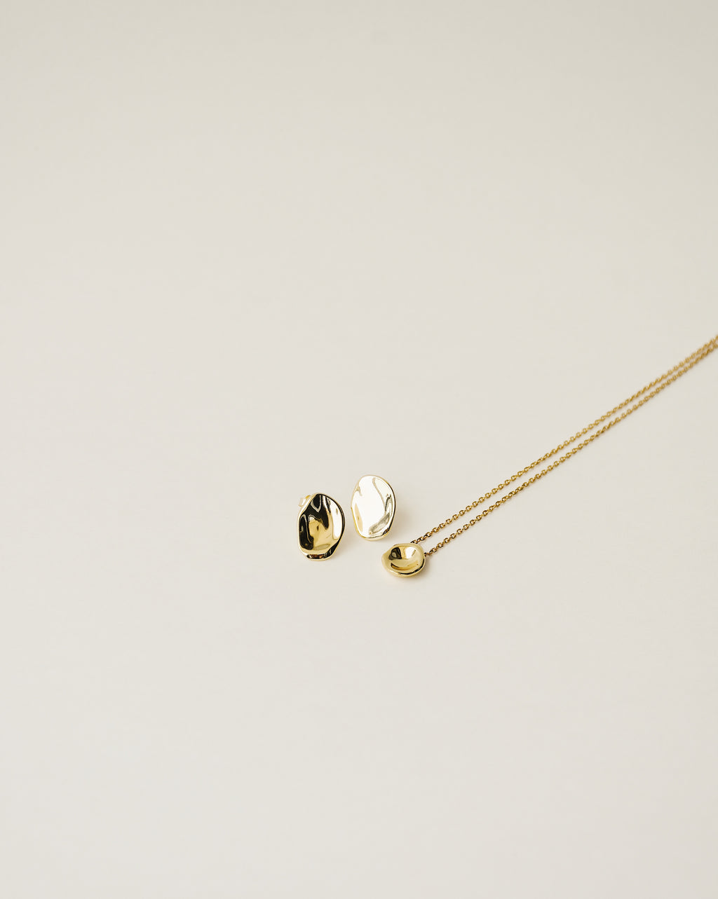 irregularly shaped tiny pendant necklace and stud earrings handcrafted from 925 sterling silver plated in 18k gold. 2020 slow fashion trend.