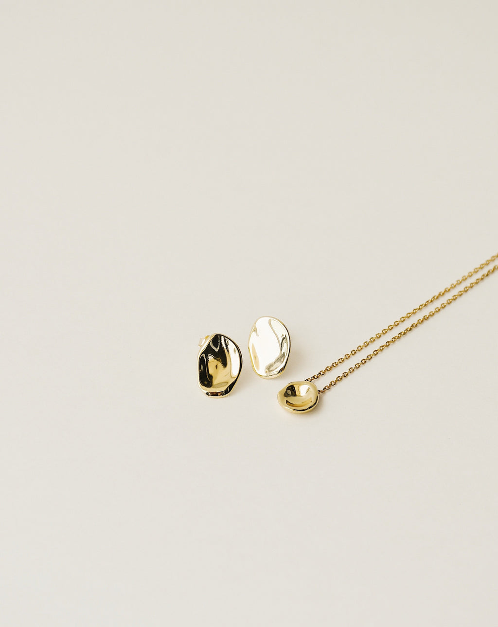 irregularly shaped stud earrings and pendant necklace handcrafted from 925 sterling silver plated in 18k gold. 2020 slow fashion trend.