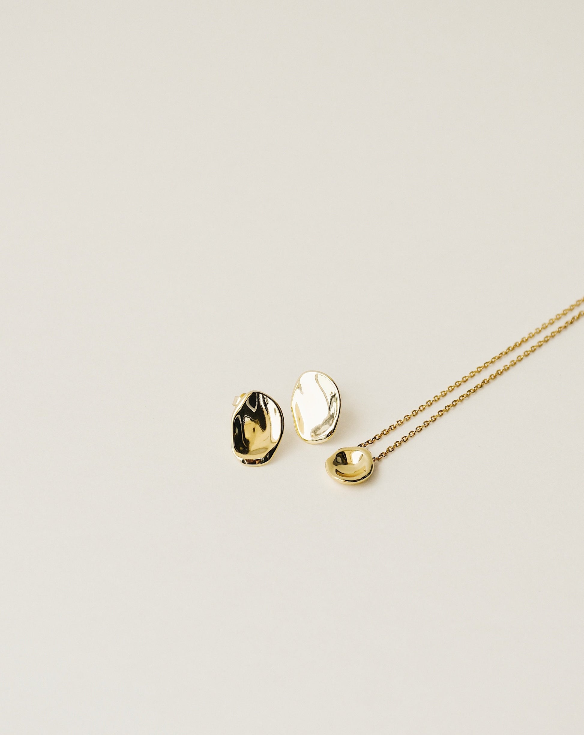 irregularly shaped stud earrings and pendant necklace handcrafted from 925 sterling silver plated in 18k gold. 2020 slow fashion trend.