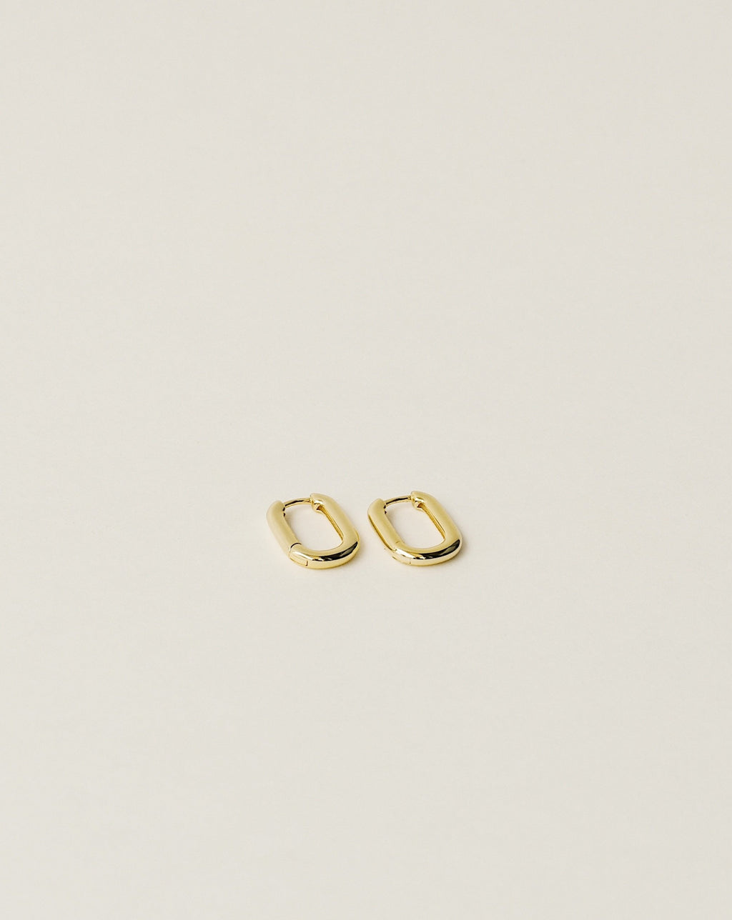 timeless and versatile oval shape huggie earrings handcrafted from 925 sterling silver plated in 18k gold. slow fashion trend 2020.