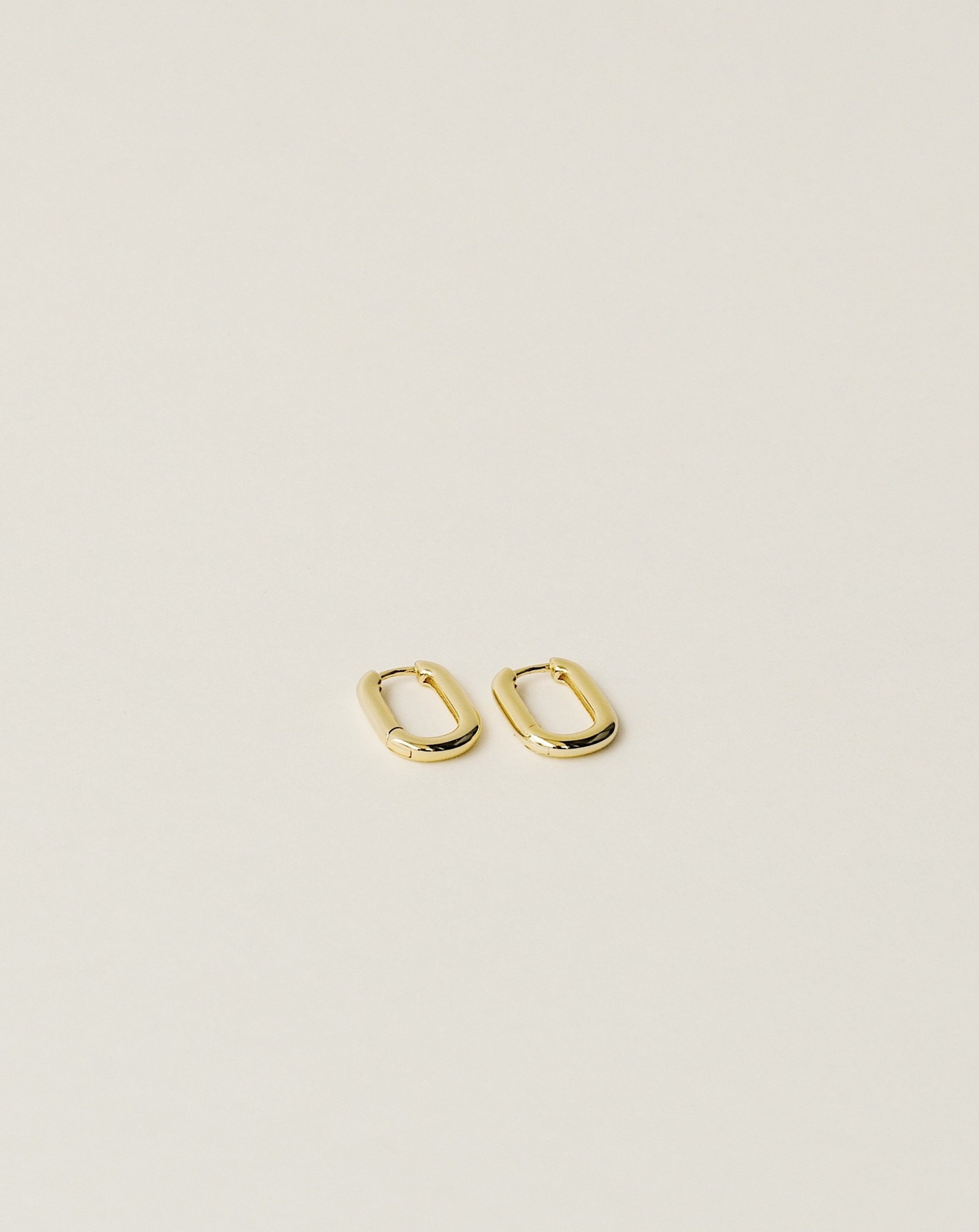 timeless and versatile oval shape huggie earrings handcrafted from 925 sterling silver plated in 18k gold. slow fashion trend 2020.