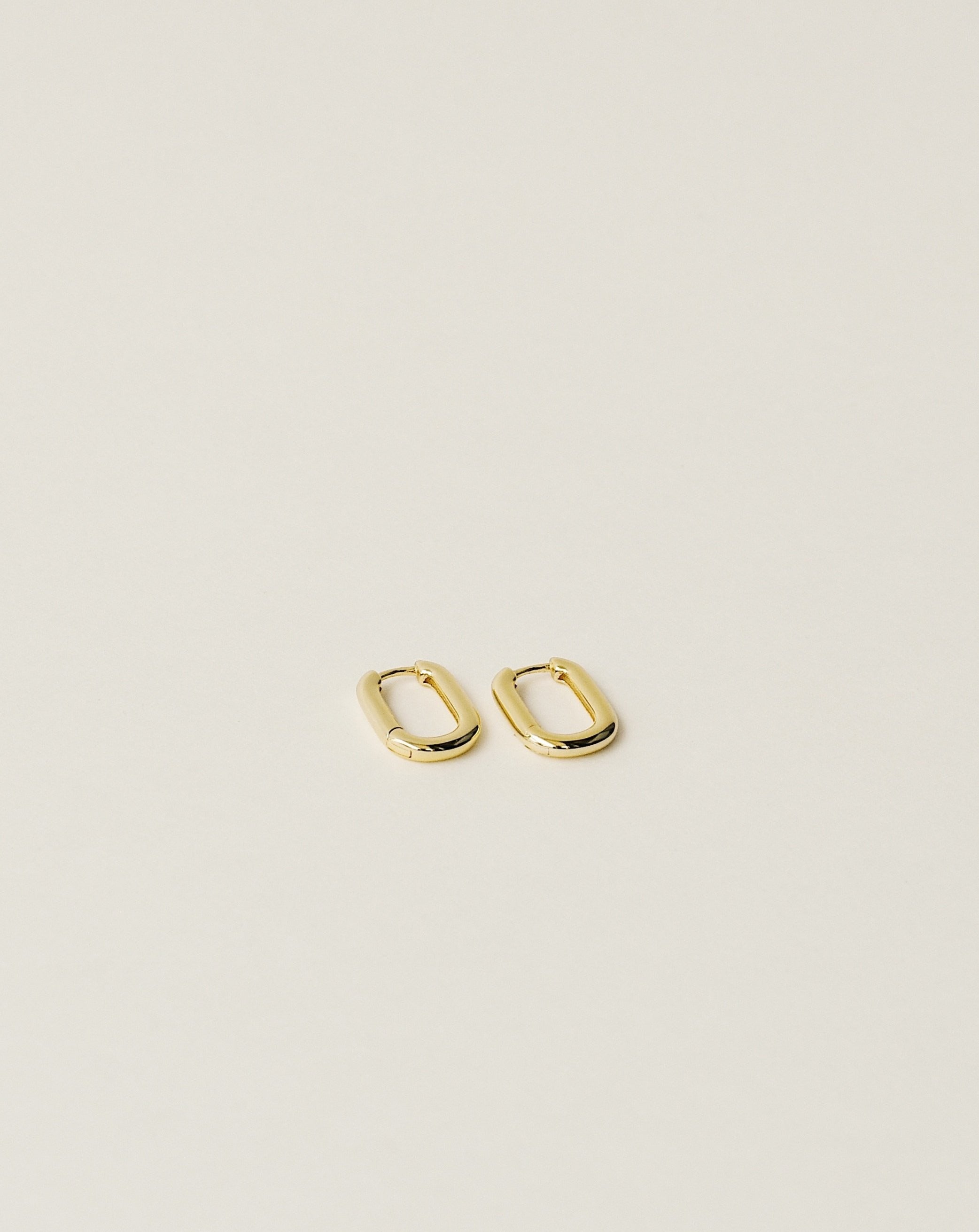 timeless and versatile oval shape huggie earrings handcrafted from 925 sterling silver plated in 18k gold. slow fashion trend 2020.