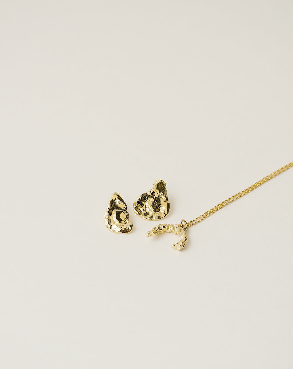 irregularly shaped stud earrings and necklace handcrafted from 925 sterling silver plated in 18k gold. 2020 slow fashion trend.