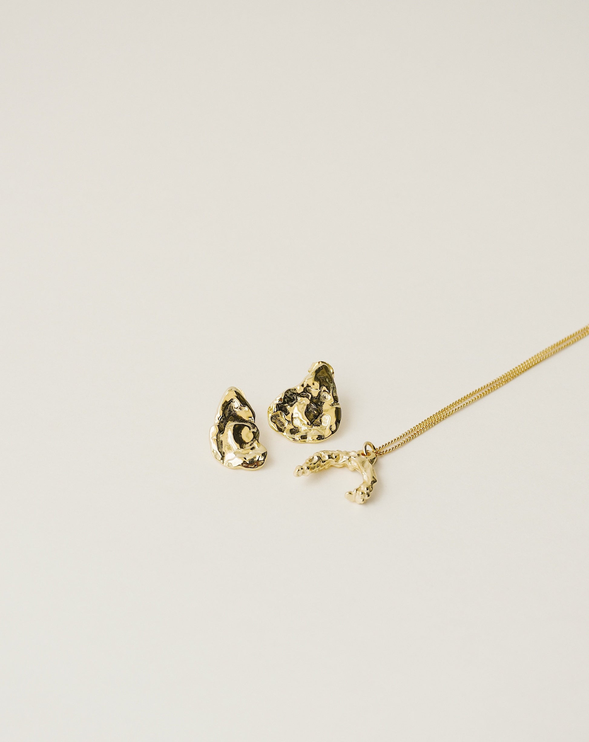 irregularly shaped stud earrings and necklace handcrafted from 925 sterling silver plated in 18k gold. 2020 slow fashion trend.