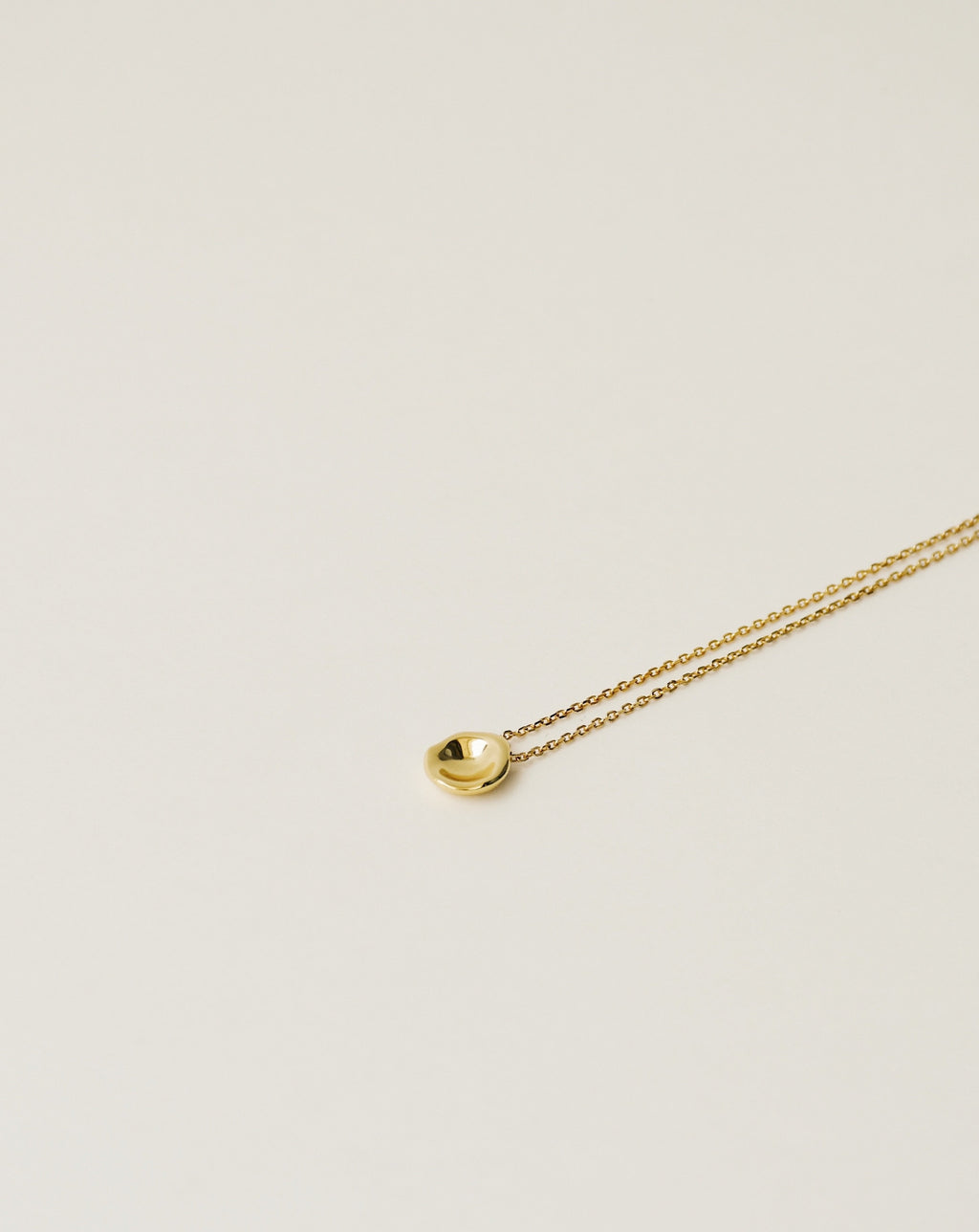 irregularly shaped tiny pendant necklace handcrafted from 925 sterling silver plated in 18k gold. 2020 slow fashion trend.