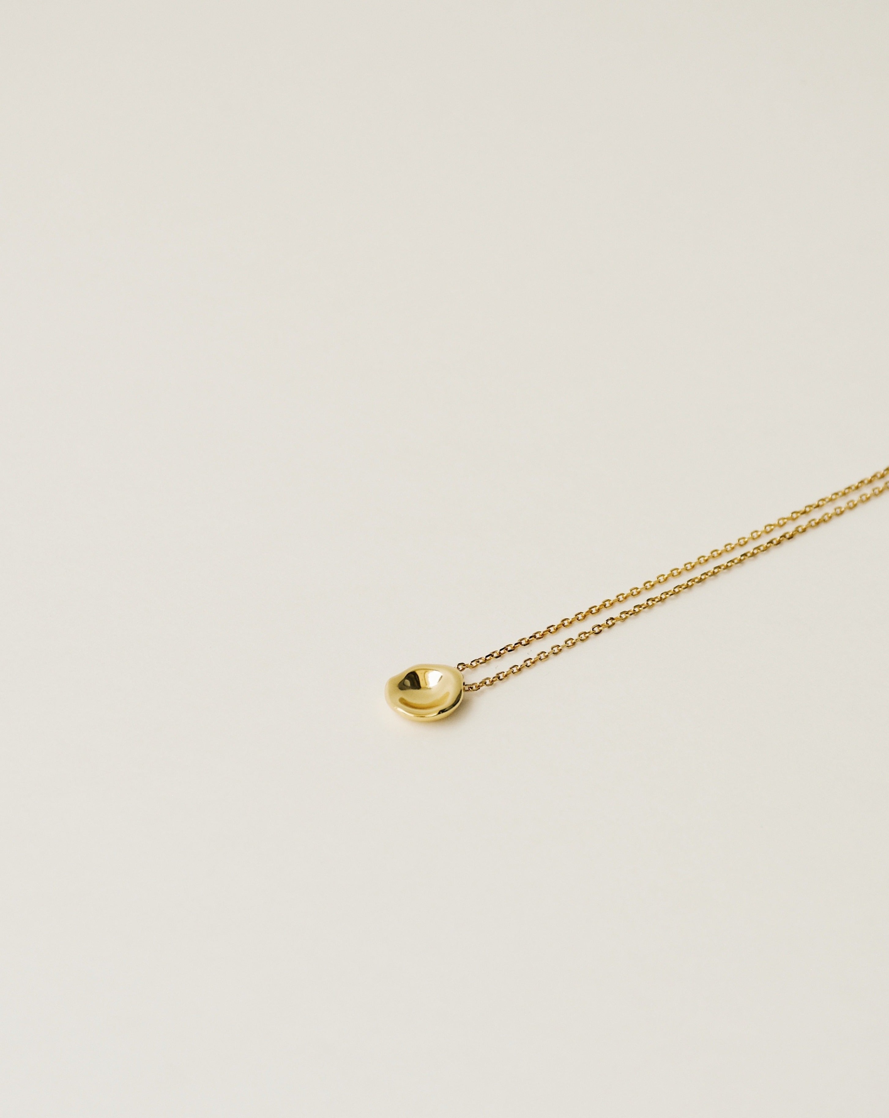 irregularly shaped tiny pendant necklace handcrafted from 925 sterling silver plated in 18k gold. 2020 slow fashion trend.