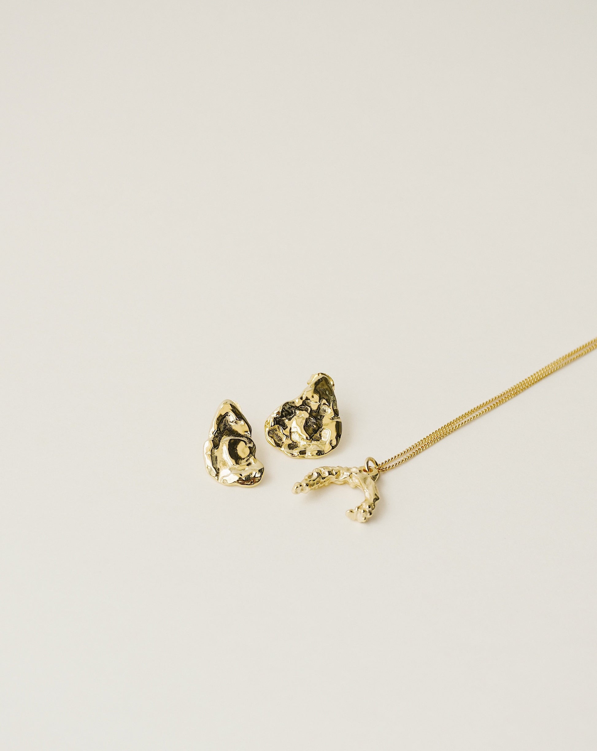 irregularly shaped stud earrings and necklace handcrafted from 925 sterling silver plated in 18k gold. 2020 slow fashion trend.