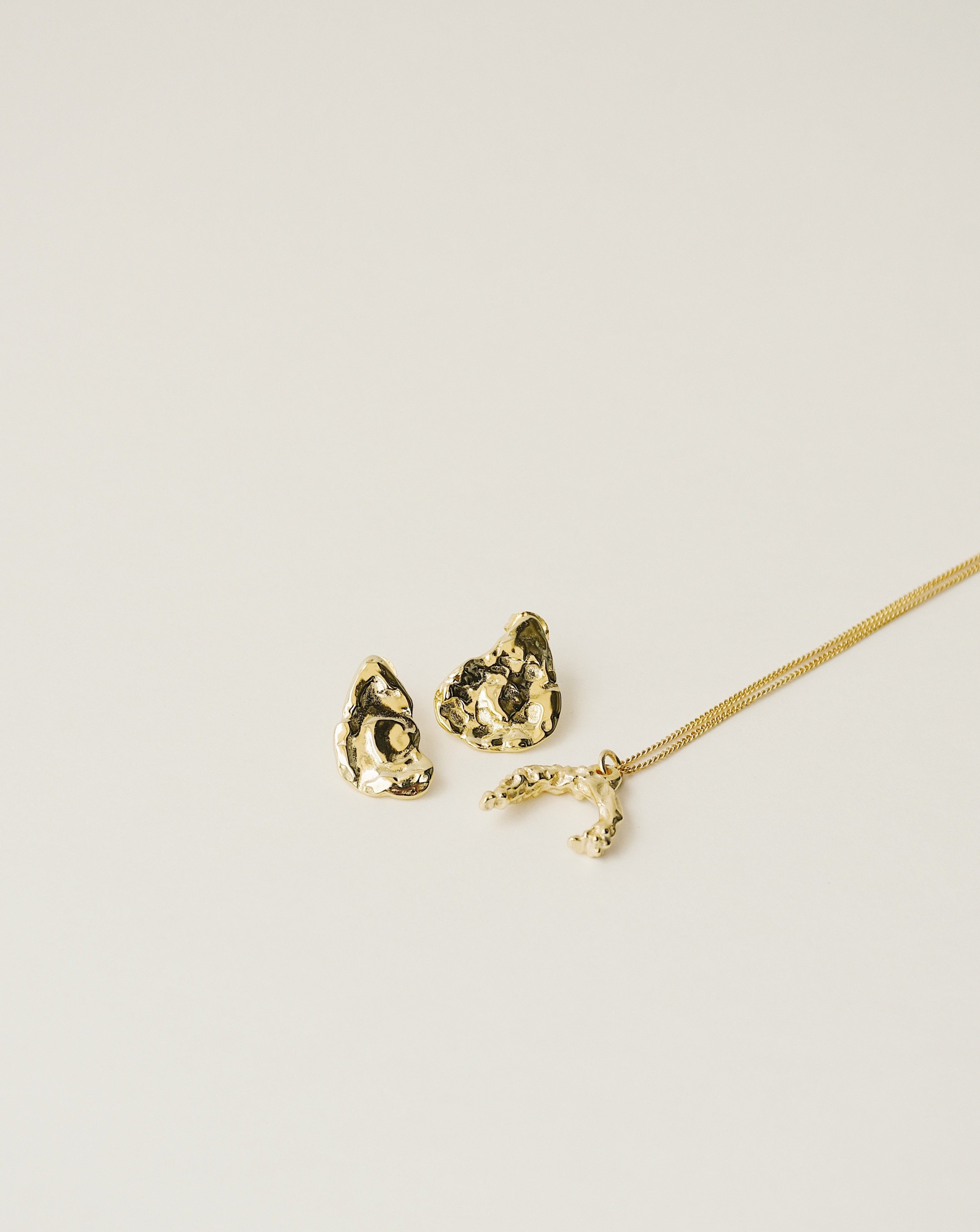 irregularly shaped stud earrings and necklace handcrafted from 925 sterling silver plated in 18k gold. 2020 slow fashion trend.